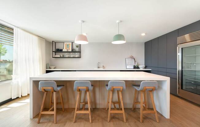 A kitchen with a white countertop and wooden bar stools.