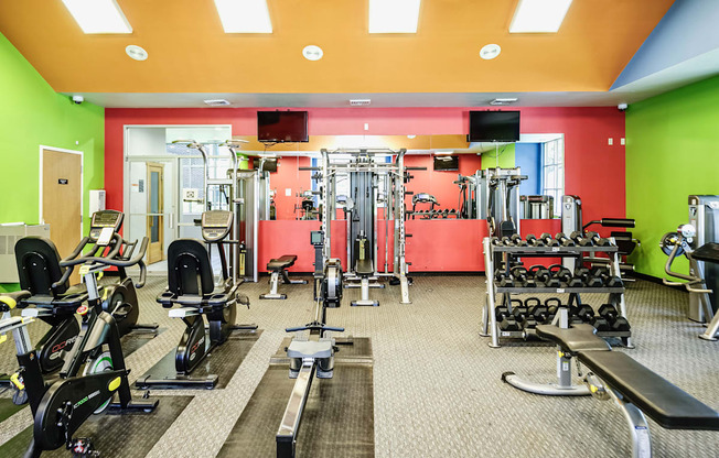 A gym with a variety of equipment including treadmills, weights, and exercise machines.