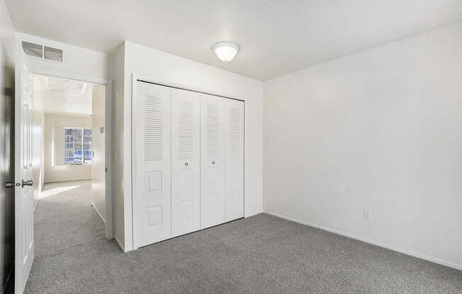 A white room with a grey carpet and a white door.
