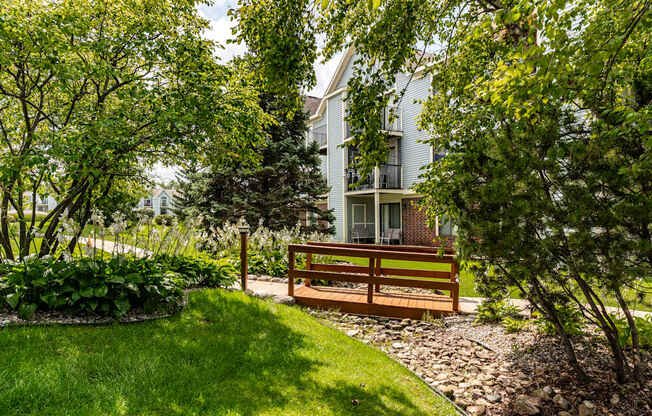 A bench is situated in a garden with a building in the background
