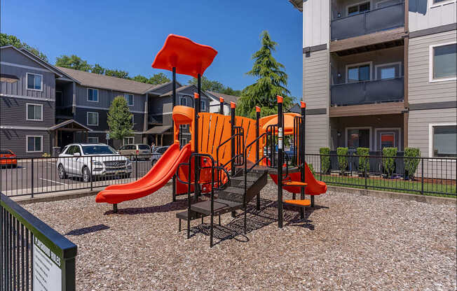 A playground with a red slide and orange structure at Timberridge Place Apartment Homes, Albany, Oregon