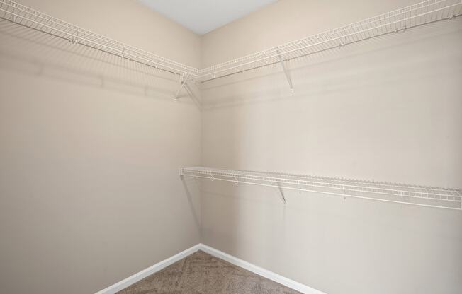 an empty closet in a home with white walls and carpet