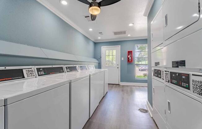 A laundry room with a row of washers and dryers.
