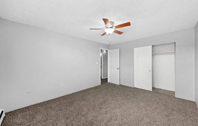 A room with a ceiling fan and carpeted floor.