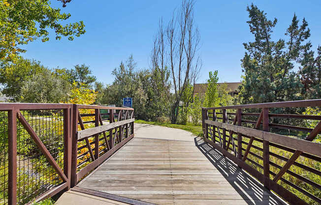 A wooden bridge with metal railings connects two land masses.