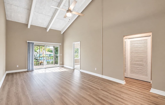 Unfurnished living room with a vaulted ceiling, exposed beams and balcony doors at Waterchase Apartments in Largo, FL.