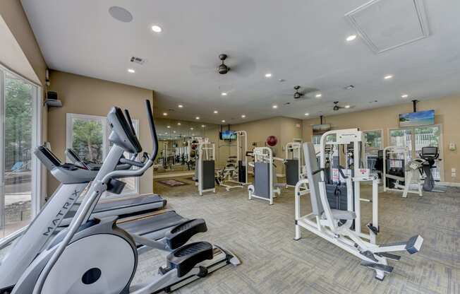 a gym with cardio equipment and weights in a building with windows