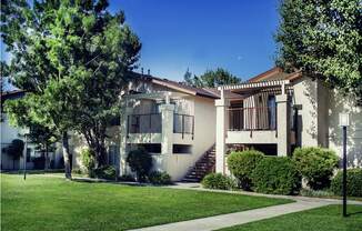 a building with a staircase in the front and a lawn in front of it