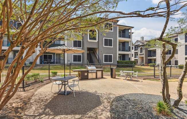 A courtyard with a picnic table surrounded by trees and apartment buildings.