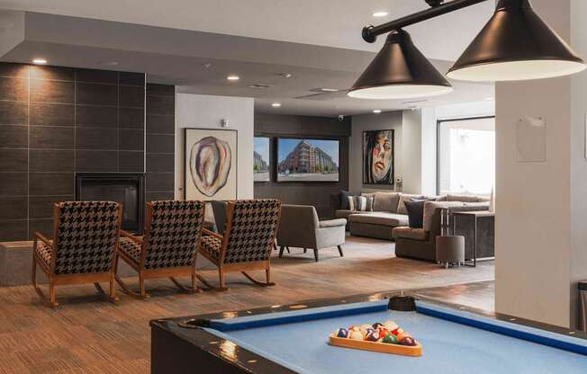 A pool table with a blue cloth and a pool game set up in a room with a fireplace and a couch at Regatta Sloans Lake Apartments, Colorado, 80204
