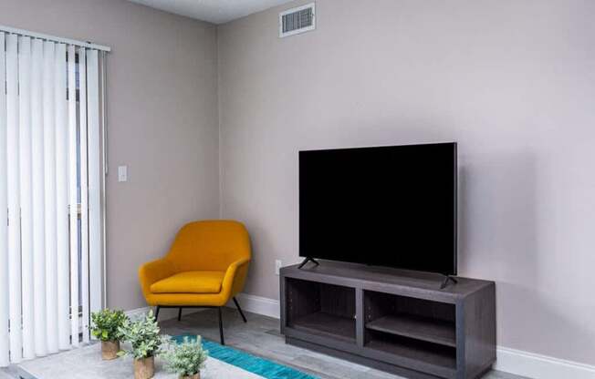 a living room with a large tv and a yellow chair