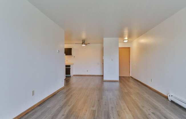 an empty living room with wood floors and white walls