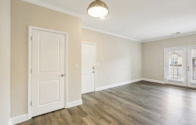 an empty living room with white doors and a window