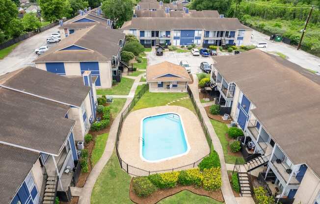 A swimming pool is surrounded by a fence and houses.