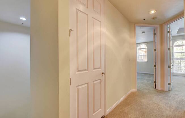 A white door is in a hallway with a tan carpet.