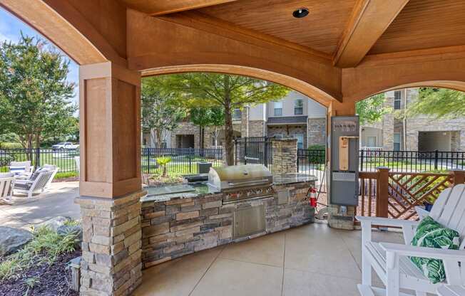 a covered patio with a grill and seating area