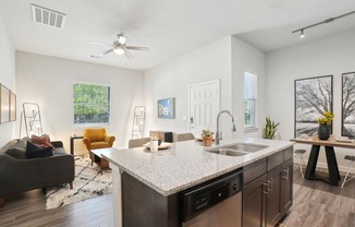 A modern kitchen with a large island and a living area with a couch and chairs.