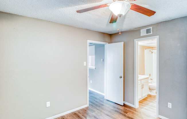 Unfurnished apartment bedroom with ceiling fan and private bathroom at Hillside Creek Apartments in Austin, TX
