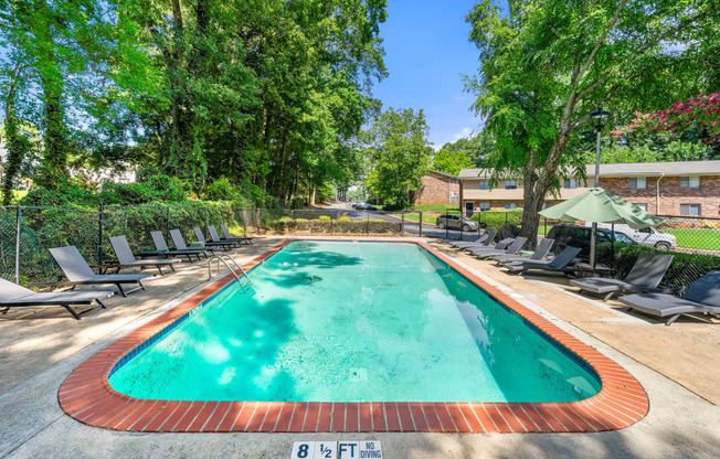 a pool with chairs and umbrellas and a building in the background