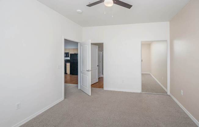 A room with a ceiling fan and carpeted floor.
