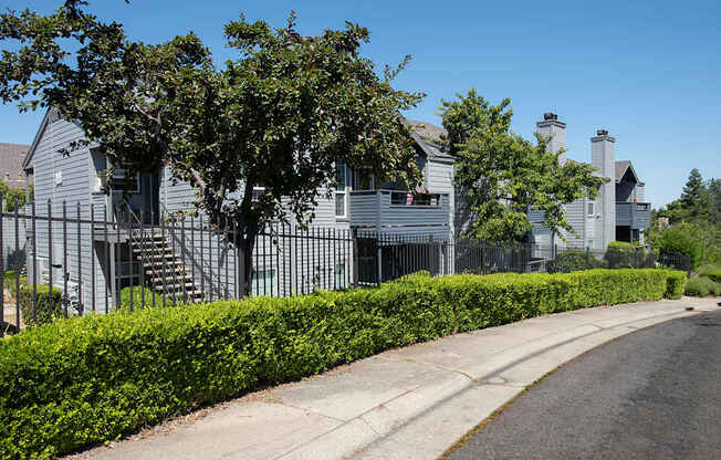 A row of apartments with a sidewalk and a hedge in front at Rocklin Gold Apartments, California, 95677