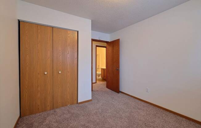 a bedroom with a closet and carpeted floors. Fargo, ND Dakota Manor Apartments