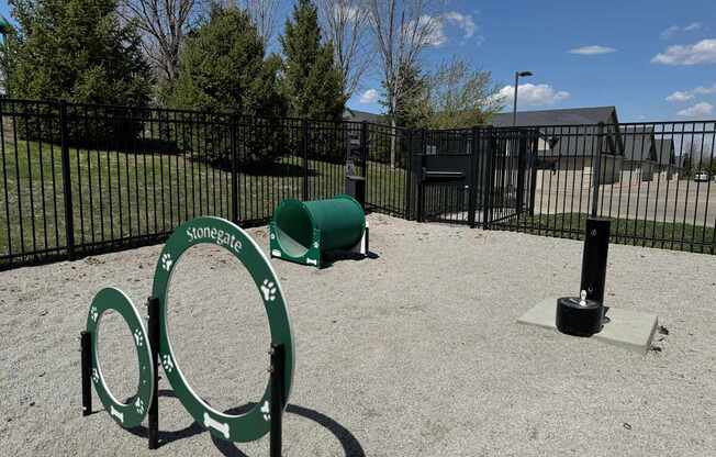 A playground with a green sign that says "Stonegate" and a green barrel.