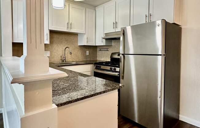 an open kitchen with stainless steel appliances and white cabinets