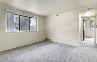 an empty living room with a large window and carpeting