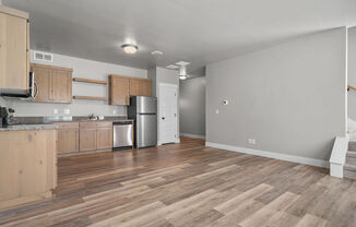 a kitchen with wooden floors and a stainless steel refrigerator