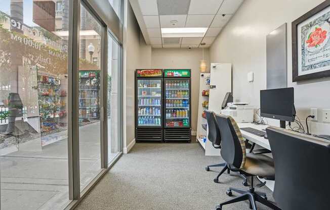 A room with a vending machine, chairs, and a desk.