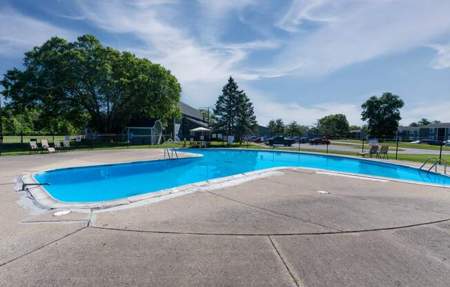 a swimming pool with trees and a blue sky in the background