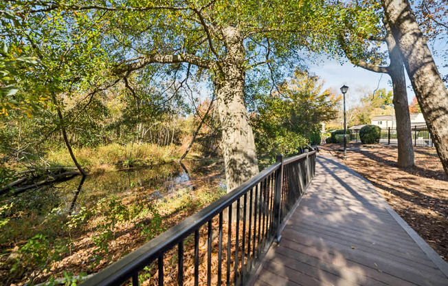 A wooden walkway with a metal railing runs through a wooded area.