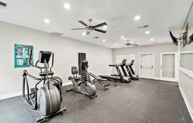A room with a grey carpet and a wall with a painting and a fan.