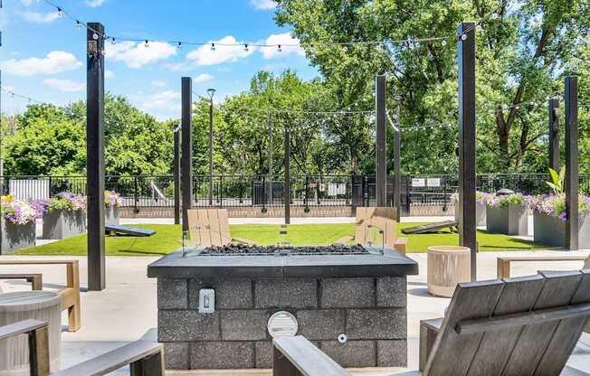 A fire pit sits in the middle of a patio surrounded by chairs.