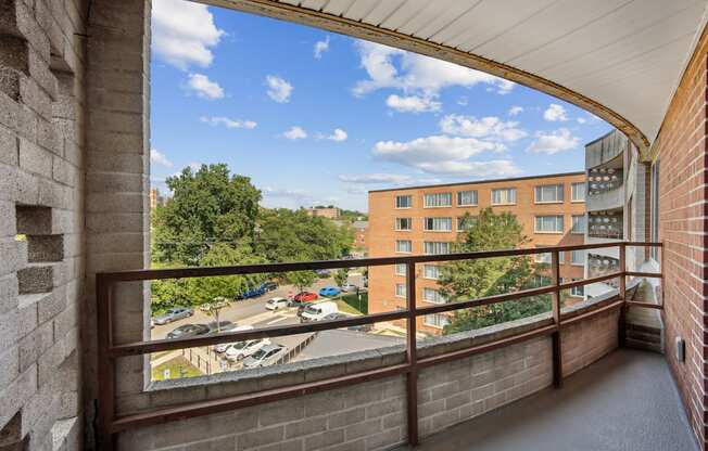A balcony with a view of a parking lot and buildings.