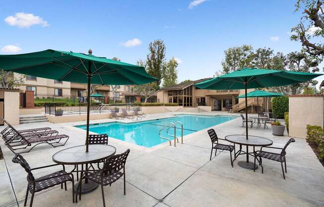 A pool area with tables and chairs and umbrellas.