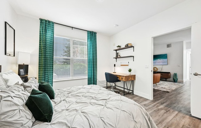 A bedroom with a large bed and a desk with a chair.