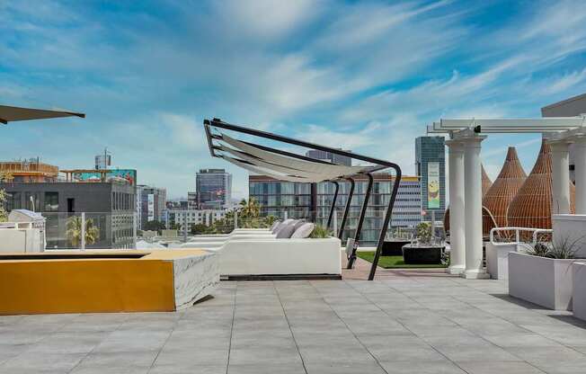 an outdoor terrace with a white couch and yellow table with white pillows and a white