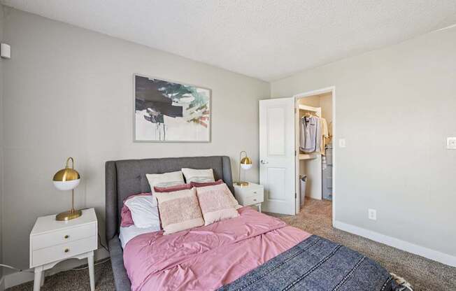 A bedroom with a bed, nightstand, and a painting on the wall.