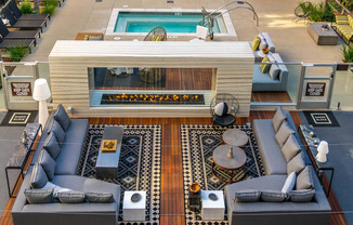 A modern outdoor living space with a pool and a fireplace.