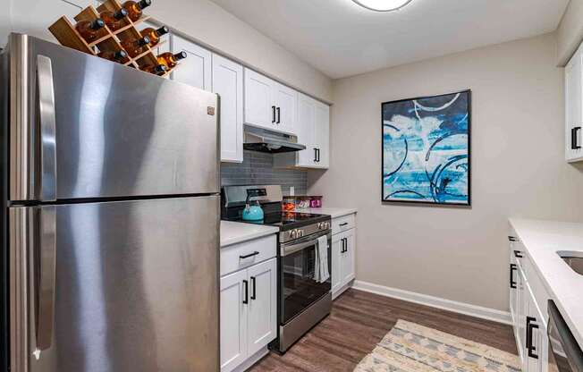 A modern kitchen with a stainless steel refrigerator and white cabinets.