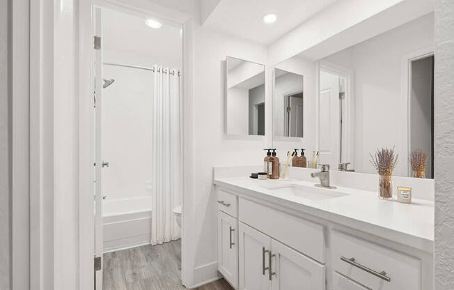 Model Bathroom with White Cabinets, Wood-Style Flooring & Shower/Tub at Horizon Apartments located in Santa Ana, CA.