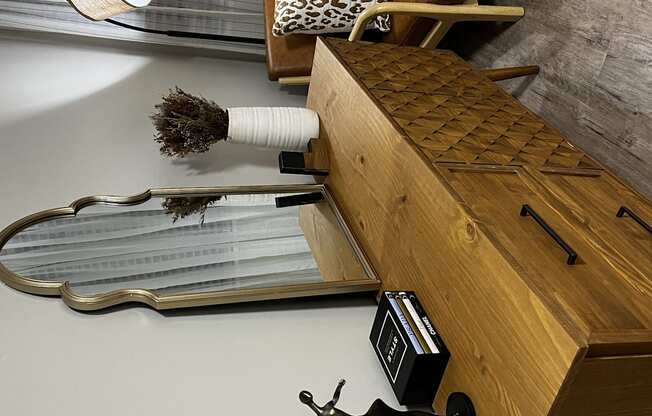 a wooden chest with a table and a broom and a table lamp