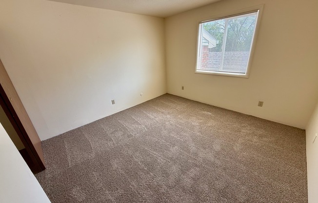 A room with a carpeted floor and a window.