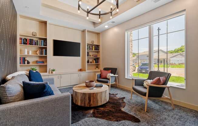 a library room with couches chairs and a coffee table in front of a large window at The Lodge at Overland, Rochester, MN, 55901