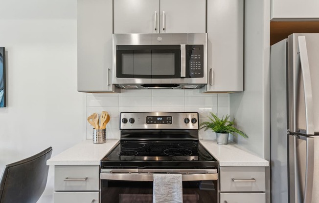 A modern kitchen with a stove, microwave, and refrigerator.