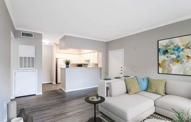 A living room with a white couch and a painting on the wall.