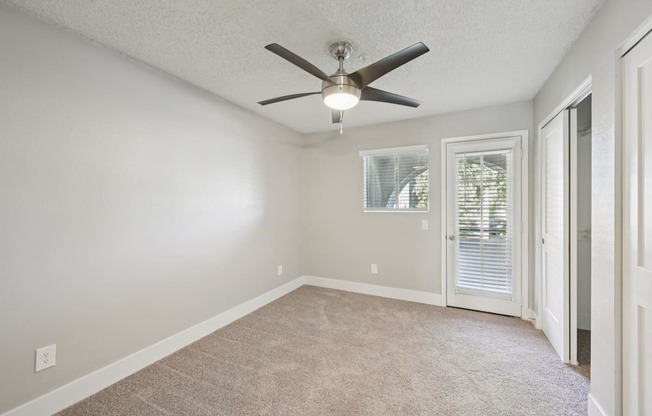 A room with a ceiling fan and carpeted floor.