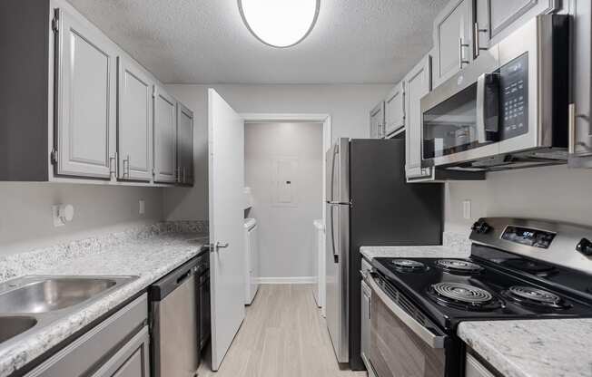 an empty kitchen with stainless steel appliances and white cabinets